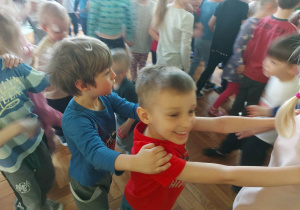 dzieci tańczą trzymając się za ramiona, tworząc tzw. wężyka