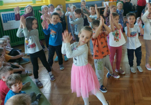 dzieci z grupy zielonej tańczą podnoszą ręce w górę i klaszcząc