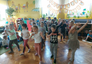 dzieci z grupy żółtej tańczą w rzędach unosząc ręce do góry