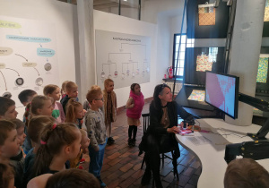 Dzieci obserwują na ekranie monitora różne materiały które prowadzący podkłada pod mikroskop