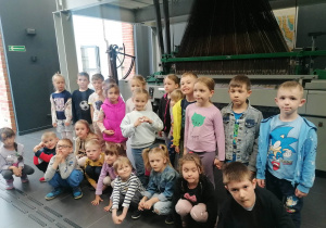 Grupa dzieci stoi na tle maszyny włókieniczej