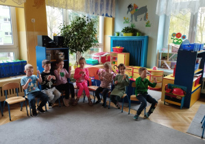 Dzieci z grupy niebieskiej siedzą na krzesłach, w rękach trzymają przybory małego chemika, pipetę i fiolke.