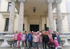 Dzieci z grupy niebieskiej stoją stoją na tle wejścia do muzeum Pałacu Herbsta