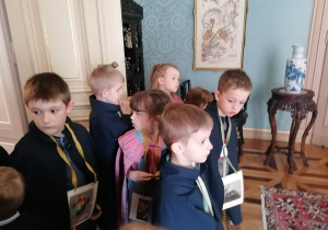 Kilkoro dzieci ogląda pokój, szukając skarbu z plakietki