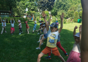 dzieci z grupy żółtej i srebrnej uczestniczą w zajęciach jogi w ogrodzie, wykonują pozycję wojownika