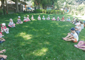 dzieci z grupy żółtej i srebrnej uczestniczą w zajęciach jogi w ogrodzie, wykonują pozycję motyla