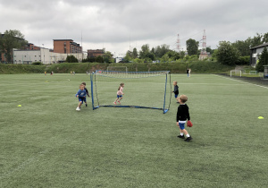 dzieci biegną na boisku za piłką