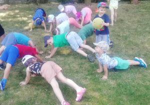Grupa dzieci biega po ogrodzie i gra w berka