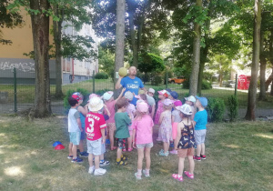 Dzieci wraz z trenerem stoją i omawiają zasady zabawy