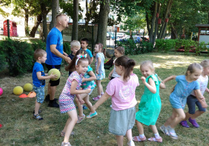 Grupa dzieci biega po ogrodzie i gra w berka