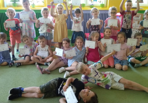 Dzieci pozują do grupowego zdjęcia, w rękach trzymają dyplomy