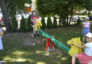 Dzieci korzystają z urządzeń na przedszkolnym placu zabaw