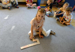 Dziewczynka układa domino na dywanie