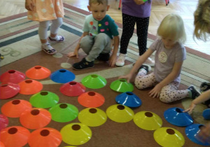 Dzieci układają słońce na dywanie z okrągłych talerzyków