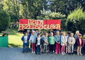 Grupa zielona pozuje do zdjęcia grupowego na tarasie przedszkolnym