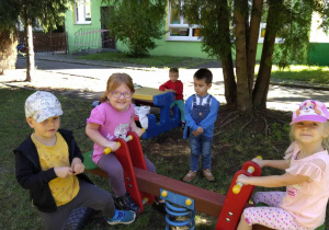 Dzieci bujają się na drewnianym koniku
