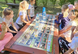 Dziewczynki losują zagadkę przy stole w ogrodzie