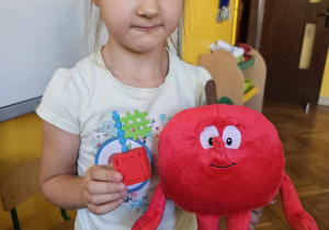 Dziewczynka prezentuje maskotkę jabłka i jabłko z klocków