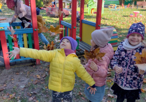 dzieci bawią się rzucając liście do góry