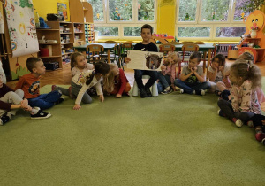 Chłopiec pokazuje dzieciom ilustrację.