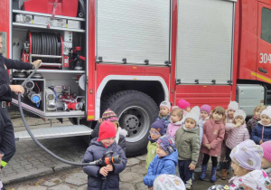 Chętne dzieci trzymają wąż strażacki