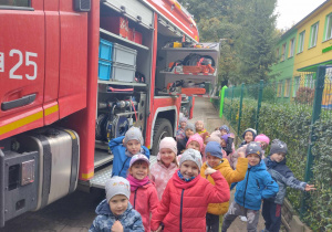 Dzieci z grupy pomarańczowej stoją przy wozie strażackim