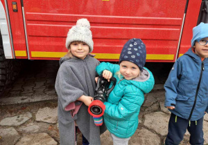 Chętne dzieci trzymają wąż strażacki