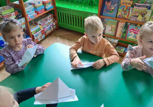 Dzieci składają łódki z białego papieru