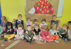 Dzieci pozują do zdjęcia grupowego, w tle jeżyk wykonany przez dzieci