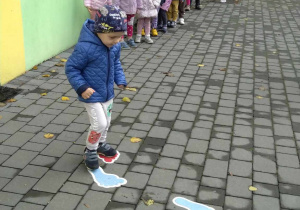 Chłopiec przechodzi po namalowanych stopach