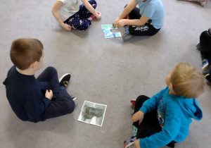 Dzieci siedzą na dywanie, składają obrazek z części