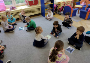 Dzieci siedzą na dywanie, składają obrazek z części