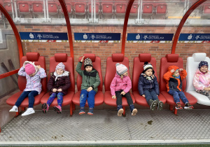 Dzieci siedzą na ławkach rezerwowych zawodników