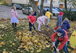Chętne dzieci grabią liście w ogrodzie przedszkolnym.
