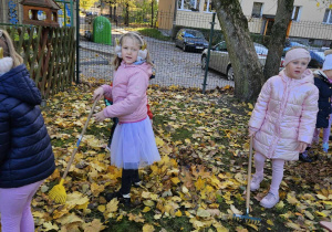 Chętne dzieci grabią liście w ogrodzie przedszkolnym.