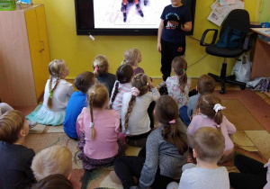 Dzieci oglądają slajd na tablicy multimedialnej oraz maskotkę - pająka