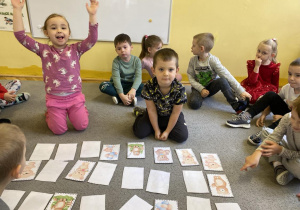 Dzieci siedzą na dywanie z ułożoną grą memory