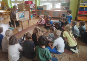 Dzieci z grupy zielonej siedzą na dywanie, P. Kasia czyta bajkę pt." O soli" przy użyciu teatrzyku Kamiszibai.