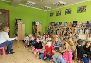 Dzieci siedzą na poduchach i słuchają opowiadania.