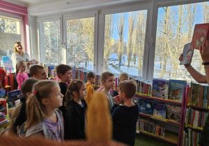 Dzieci oglądają książki na regałach.