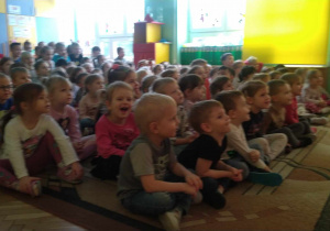 Dzieci siedzą w sali i oglądają przedstawienie
