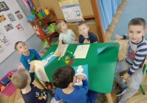 dzieci siedzą przy stoliku, wykonują bałwanka z papieru