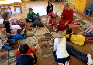 Dzieci siedzą na dywanie - jedno dziecko masuje drugie