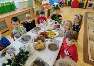 Dzieci siedzą przy stole, jedzą potrawy