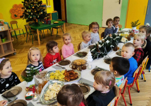 Dzieci siedzą przy stole, jedzą potrawy