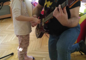 Dziewczynka próbuje zagrać na gitarze