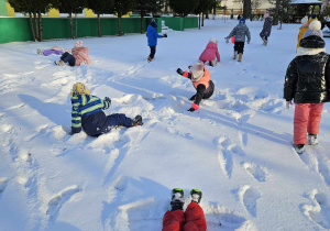 Dzieci robią aniołki na śniegu