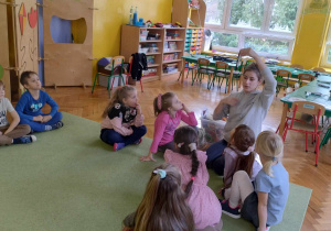 Dzieci siedzą na dywanie, prowadząca warsztaty opowiada dzieciom o zasadach korzystania z długopisu 3D oraz o jego możliwościach.