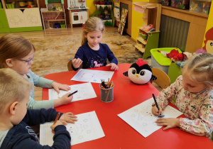 dzieci kolorują obrazek z pingwinem