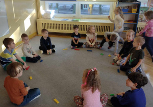 Dzieci uczestniczą w zabawie ruchowej "Kolory" z wyk. klocków